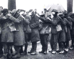 British soldiers in gas masks man a machine gun during World War I.